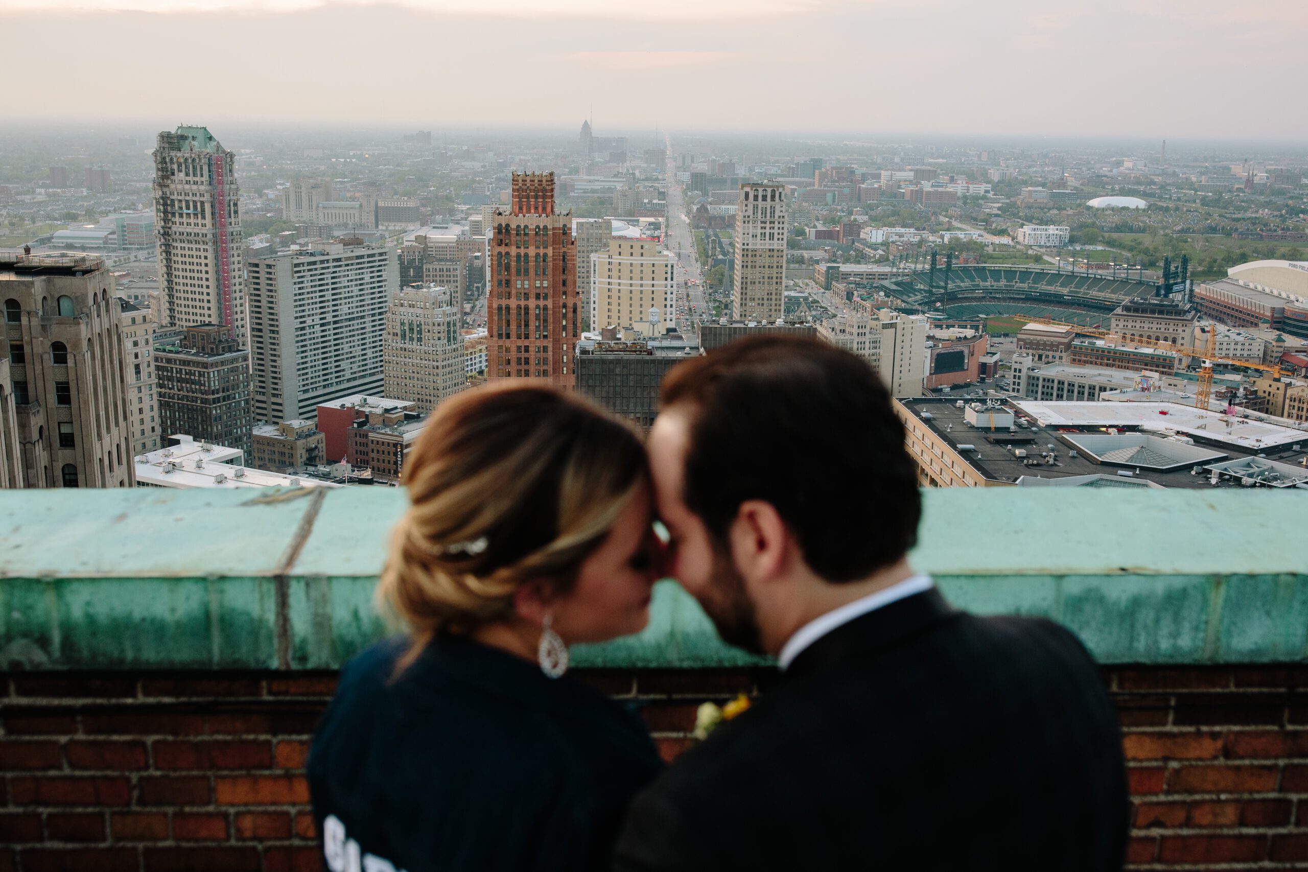 A bride and groom on the top of the Guardian Building overlooking the city of Detroit