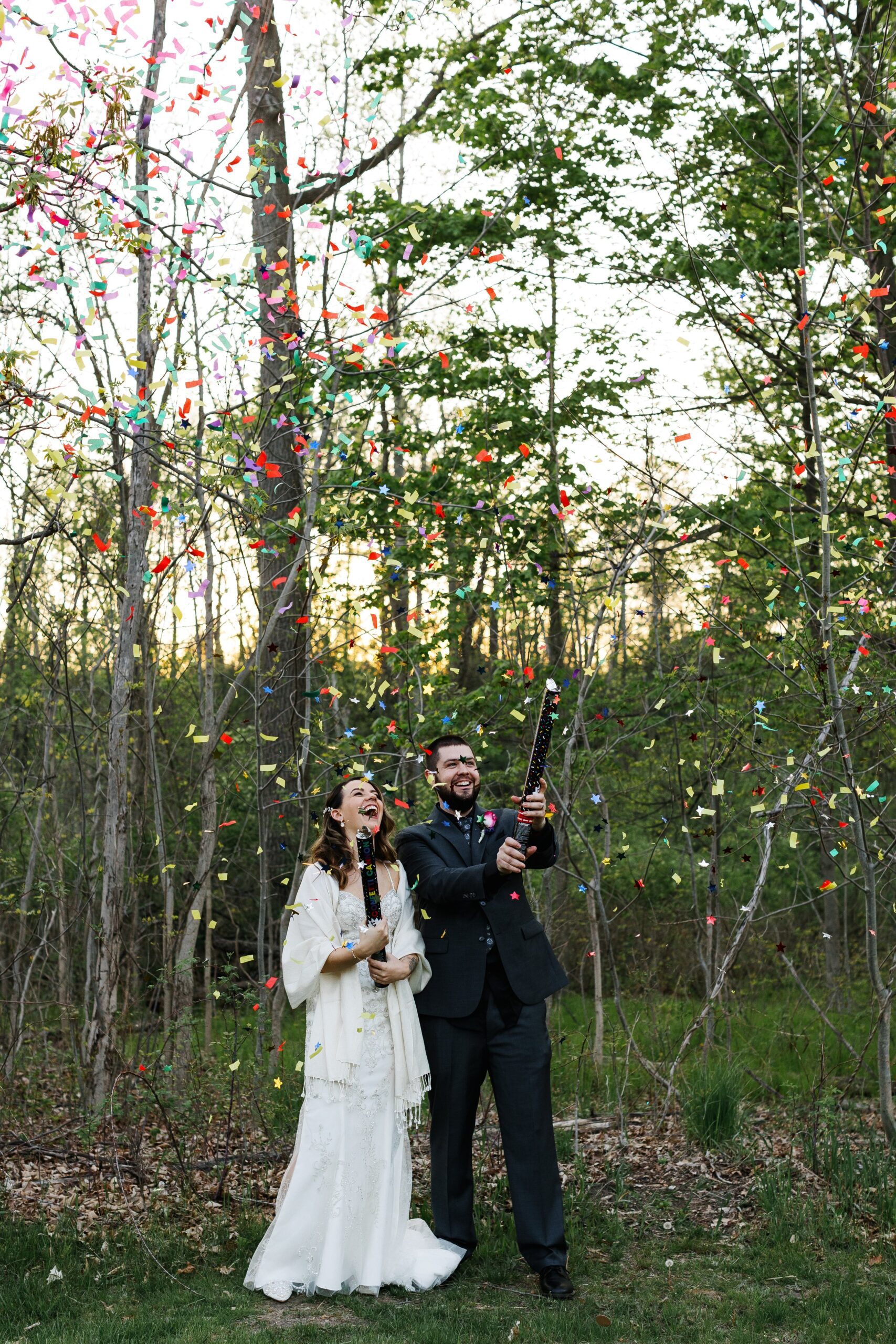 Bride and Groom popping confetti on their wedding day in the woods at Addison Oaks